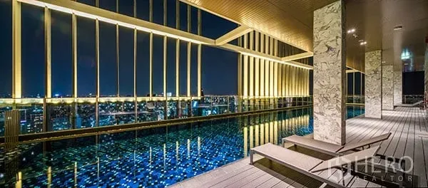 Condominium for sale in Khlong Toei, Bangkok - Rooftop infinity pool with golden vertical fins and sparkling city lights at night.