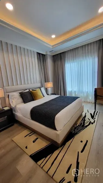 Detached House for rent or sale in Saphan Sung, Bangkok - Cozy bedroom with upholstered headboard, layered curtains, and recessed lighting.