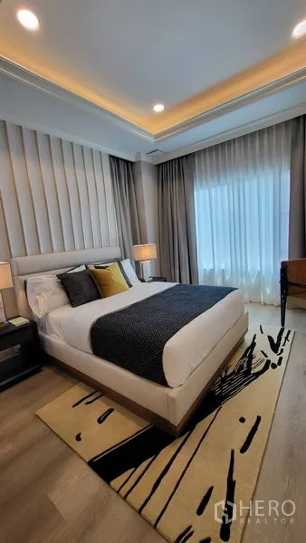 Detached House for rent or sale in Saphan Sung, Bangkok - Cozy bedroom with upholstered headboard, layered curtains, and recessed lighting.