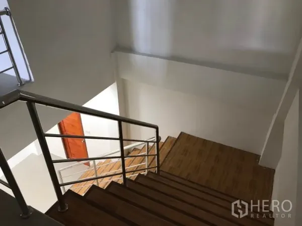 Warehouse for rent in Samut Sakhon - Interior staircase with wooden steps and stainless-steel handrail inside the office area.