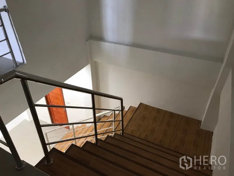 Warehouse for rent in Samut Sakhon - Interior staircase with wooden steps and stainless-steel handrail inside the office area.