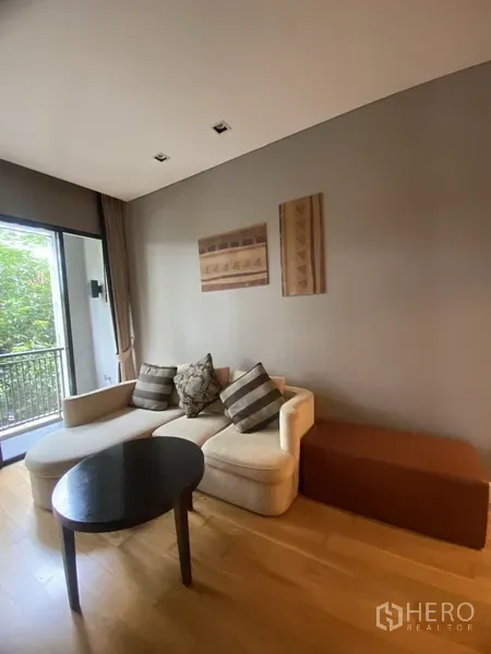 公寓 出租在Watthana, Bangkok - 客厅配L型沙发与茶几，推拉门通向观景阳台。