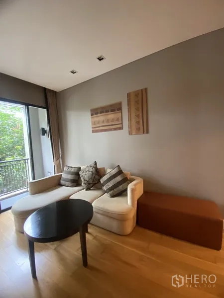 公寓 出租在Watthana, Bangkok - 客厅配L型沙发与茶几，推拉门通向观景阳台。