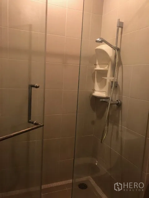 公寓 出租在Khlong San, Bangkok - 浴室为玻璃淋浴间与手持花洒，米色墙砖。