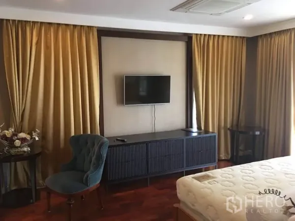 Detached House for rent in Bang Phli, Samut Prakan - Master bedroom corner with wall-mounted TV, long media cabinet, and gold floor-to-ceiling curtains.