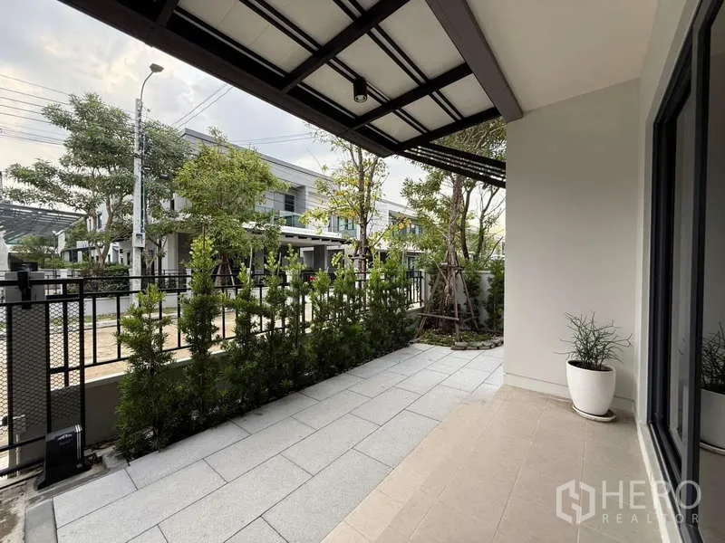 บ้าน ขายในBang Phli, Samut Prakan - ชานหน้าบ้านมุงหลังคาปูพื้นกระเบื้อง พร้อมแนวต้นไม้ริมรั้วเพิ่มความเป็นส่วนตัว