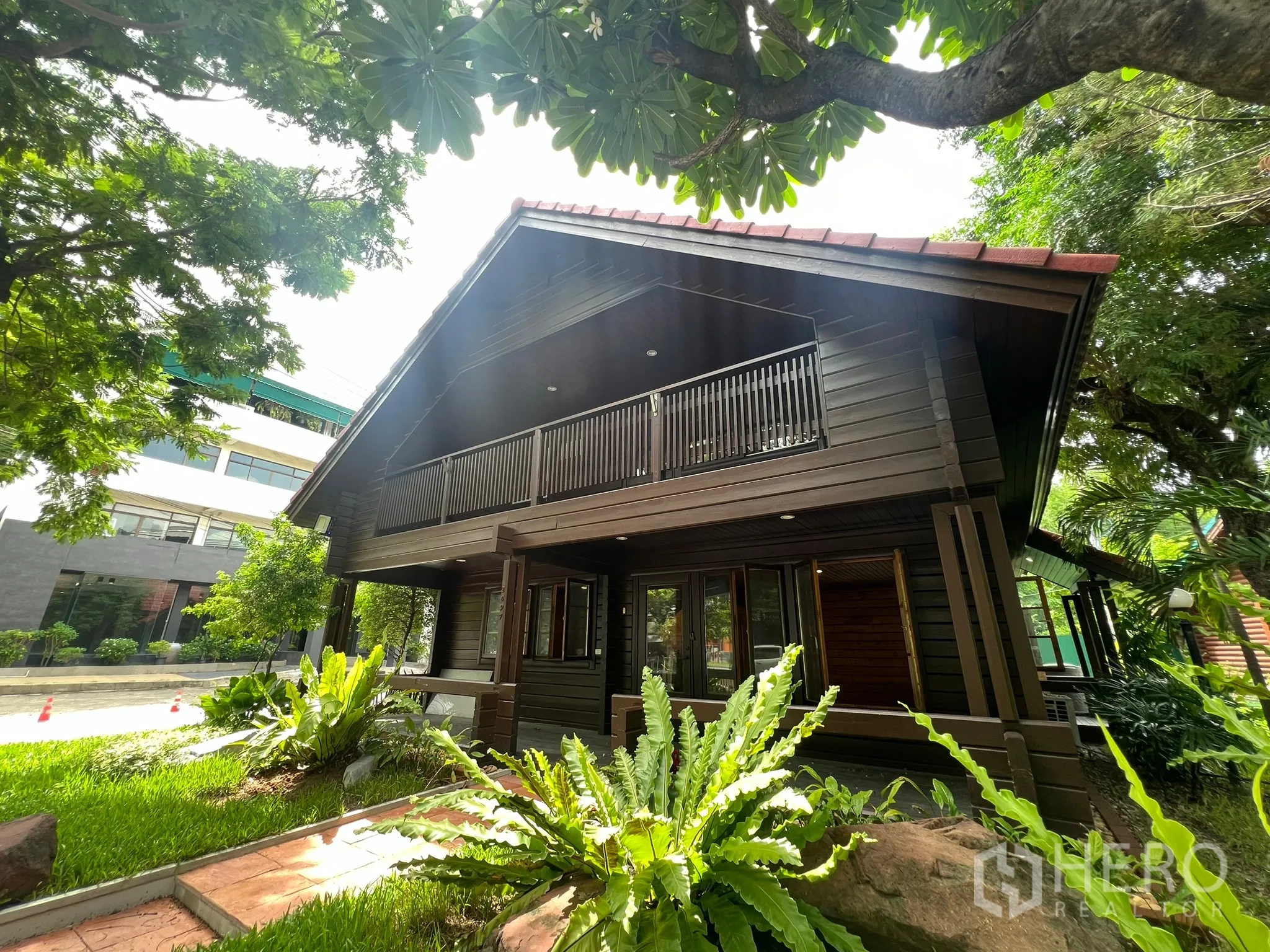 带办公室的家 出租在Suan Luang, Bangkok - 木质外立面家用办公室侧景，绿树环绕临近安静街道。