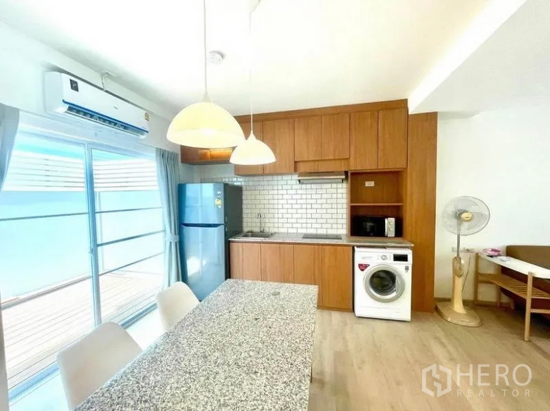 联排别墅 出租在Prawet, Bangkok - 开放式厨房配石材中岛、吊灯、地铁砖墙、冰箱与洗衣机。