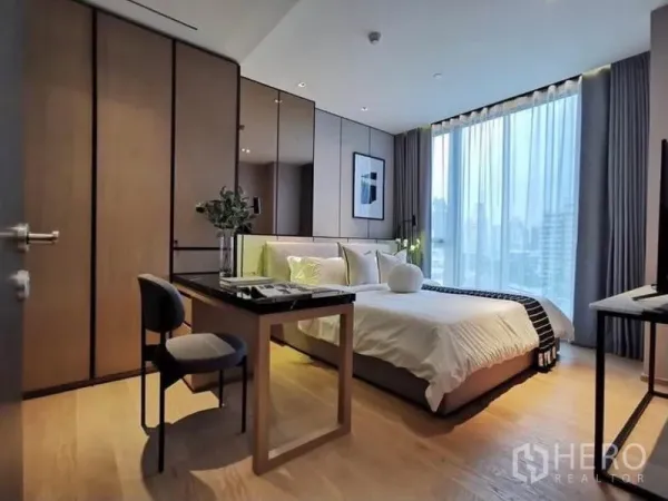 Condominium for rent in Khlong Toei, Bangkok - Bedroom with desk and wardrobe facing large window and city skyline