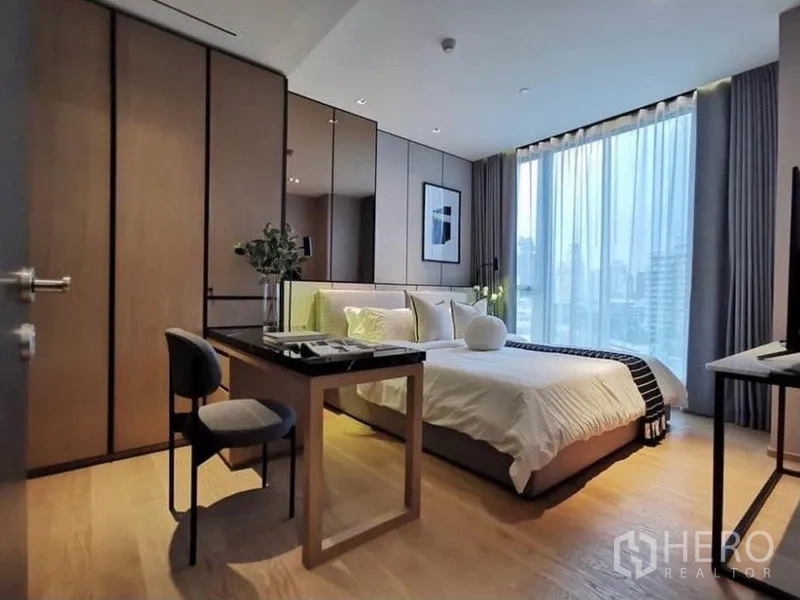 Condominium for rent in Khlong Toei, Bangkok - Bedroom with desk and wardrobe facing large window and city skyline