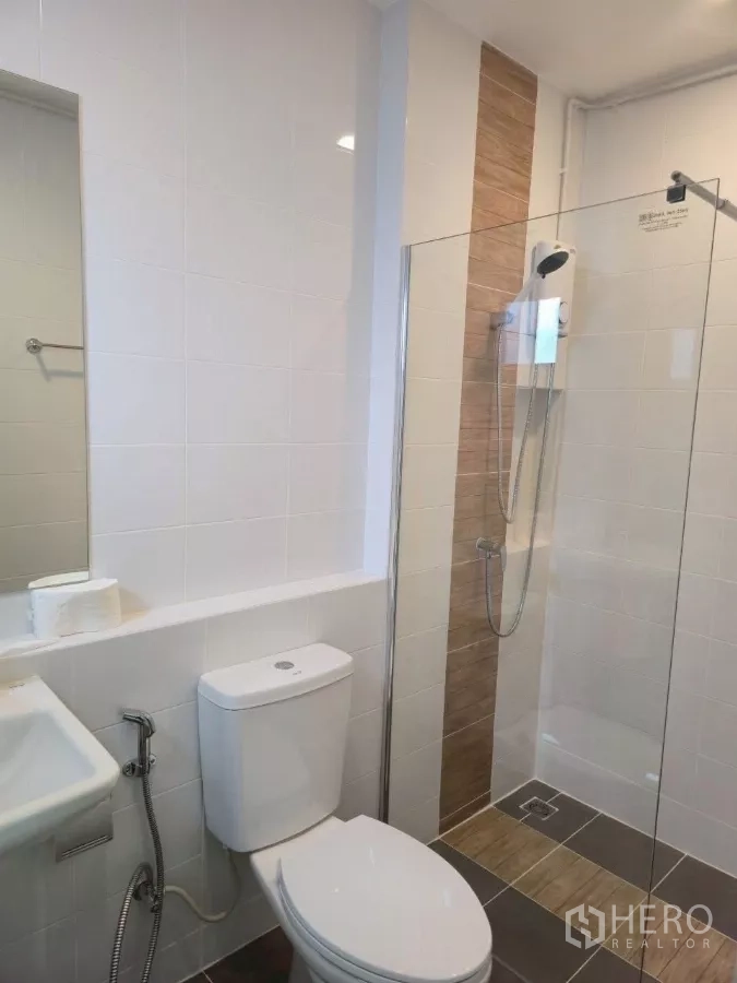 Townhouse for rent in Bang Phli, Samut Prakan - Clean bathroom with glass-enclosed shower, handheld shower and water heater on white tiles.