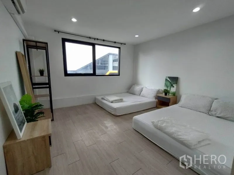 Home Office for rent - Large bedroom with two floor mattresses beneath a wide window and recessed ceiling lights.
