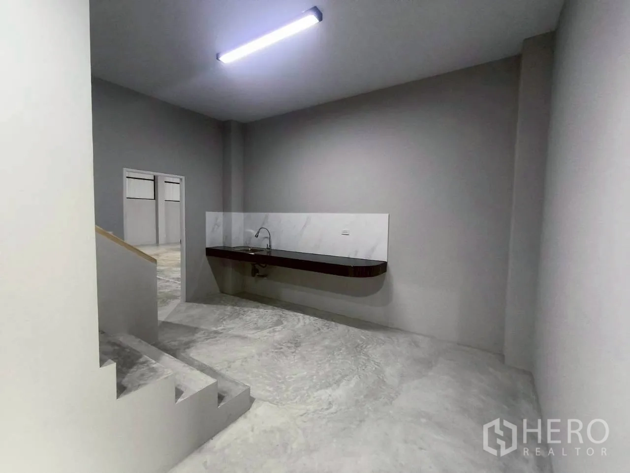 Warehouse for rent in Mueang Nonthaburi, Nonthaburi - Ground-floor area with a built-in sink counter and staircase to upper levels.