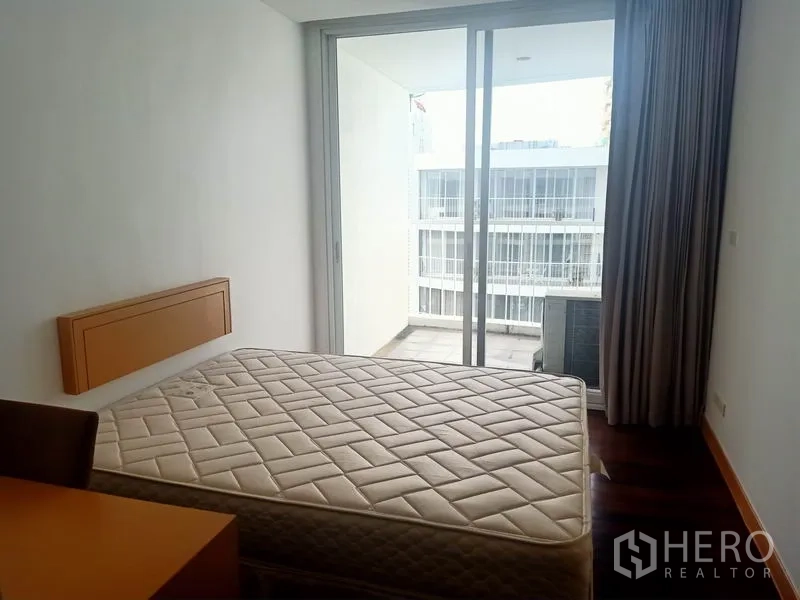 公寓 出租在Watthana, Bangkok - 卧室通过推拉玻璃门连接阳台，可见庭院景观。