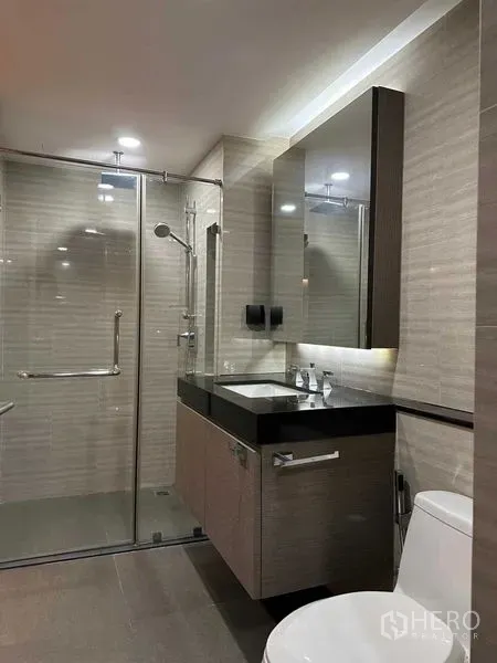 公寓 出售在Pathum Wan, Bangkok - 现代浴室，玻璃淋浴间与带灯洗手台和大镜子。