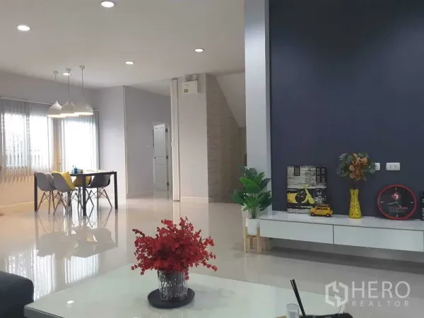 Detached House for rent in Lam Luk Ka, Pathum Thani - Bright open-plan living and dining area with pendant lights, glossy floors and a dark feature wall cabinet.