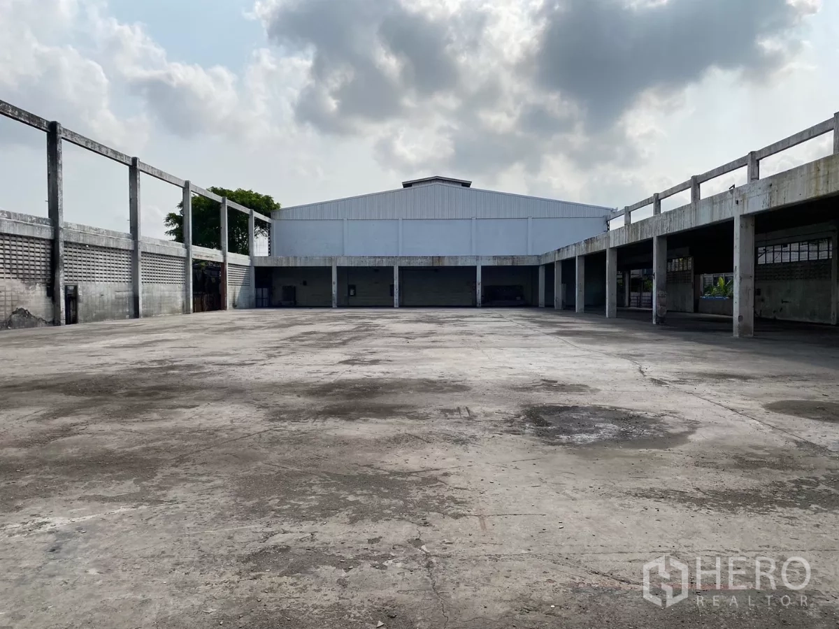 Factory for sale in Bang Phli, Samut Prakan - Central concrete yard surrounded by covered bays and a white metal-roof warehouse.