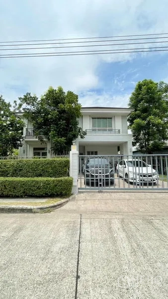 Detached House for sale in Lat Krabang, Bangkok - Front elevation of the two-storey house with trimmed hedge and metal gate.