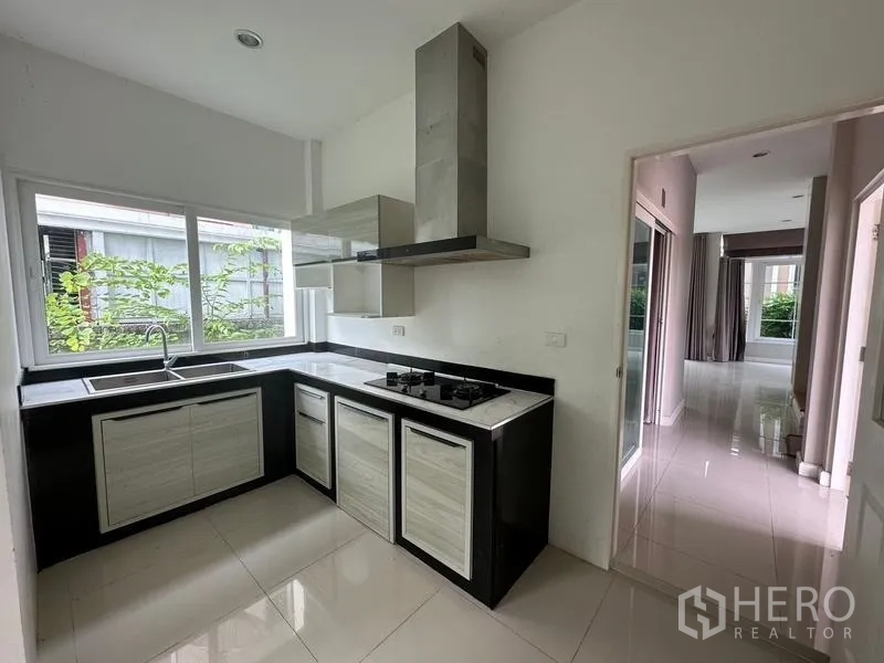 Detached House for sale in Bang Khen, Bangkok - Fitted kitchen with L-shaped counters, gas hob, hood, and large window.