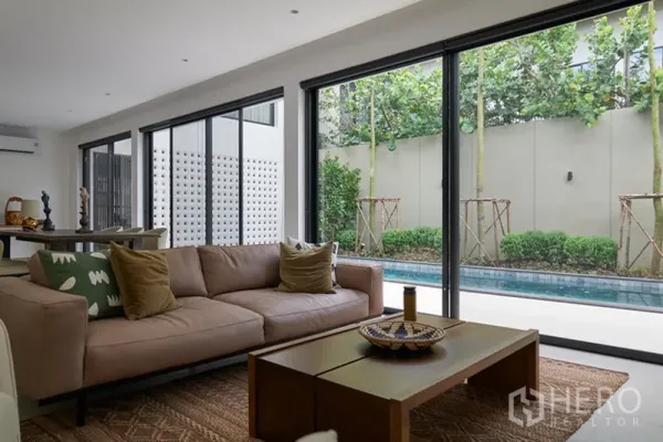Detached House for rent in Watthana, Bangkok - Open-plan living room with sliding glass doors overlooking the pool terrace.