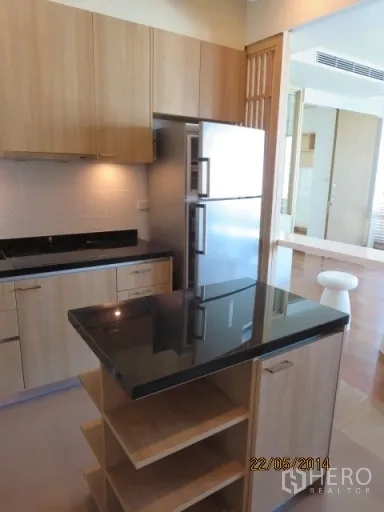 Condominium for rent in Bang Rak, Bangkok - Kitchen island and stainless-steel refrigerator in a fitted contemporary kitchen.