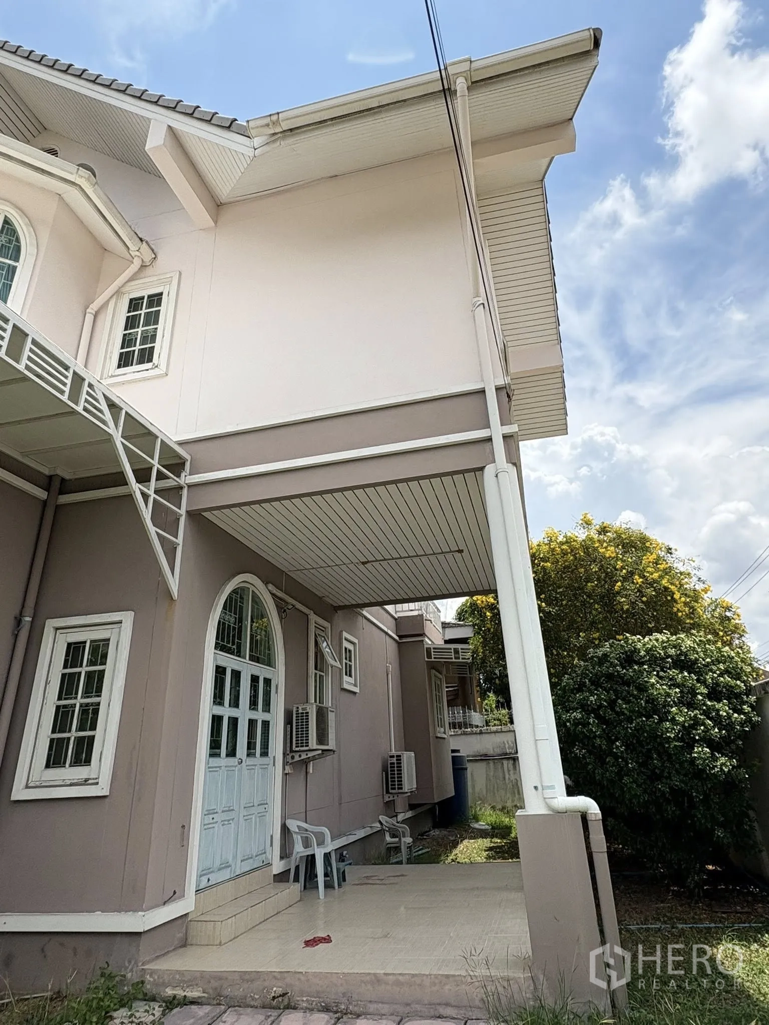 独立式住宅 出售在Phra Khanong, Bangkok - 侧边有顶平台，立柱、拱门与室外空调机组。