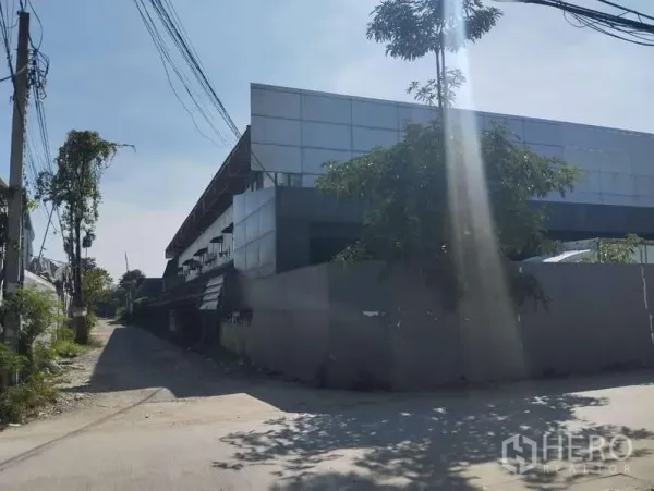 โรงงาน ขายในSaphan Sung, Bangkok - ภายนอกโรงงานสมัยใหม่ริมซอยเงียบในเขตสะพานสูง ผนังเมทัลชีทและต้นไม้