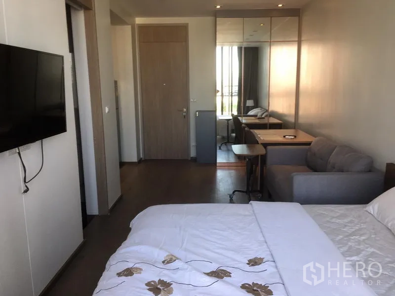 公寓 出租在Khlong Toei, Bangkok - 从床望向入口，壁挂电视、工作桌、沙发与镜面衣柜。