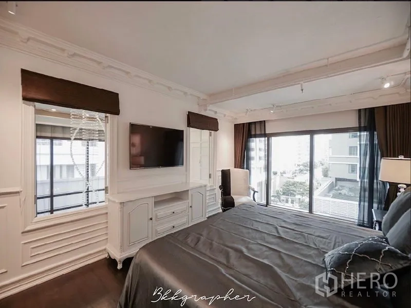 公寓 出租或出售在Khlong Toei, Bangkok - 卧室内置电视柜，推拉阳台门，面向城市景观。