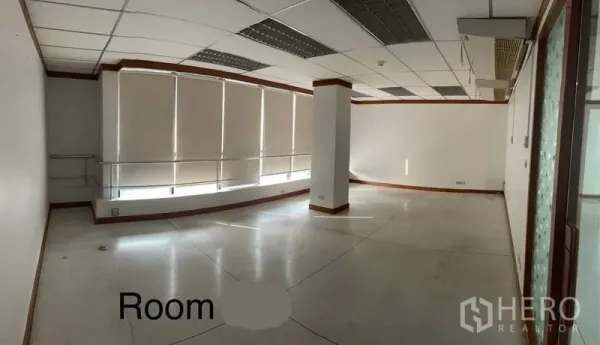 Office Space for rent in Khlong Toei, Bangkok - Spacious office area with a curved window wall, blinds, central column, and ceiling lighting.