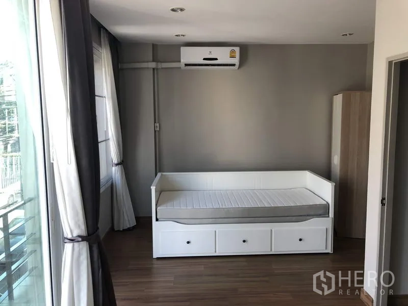 Townhouse for rent in Yan Nawa, Bangkok - Sunlit bedroom with daybed, wood flooring, balcony doors and air conditioning.
