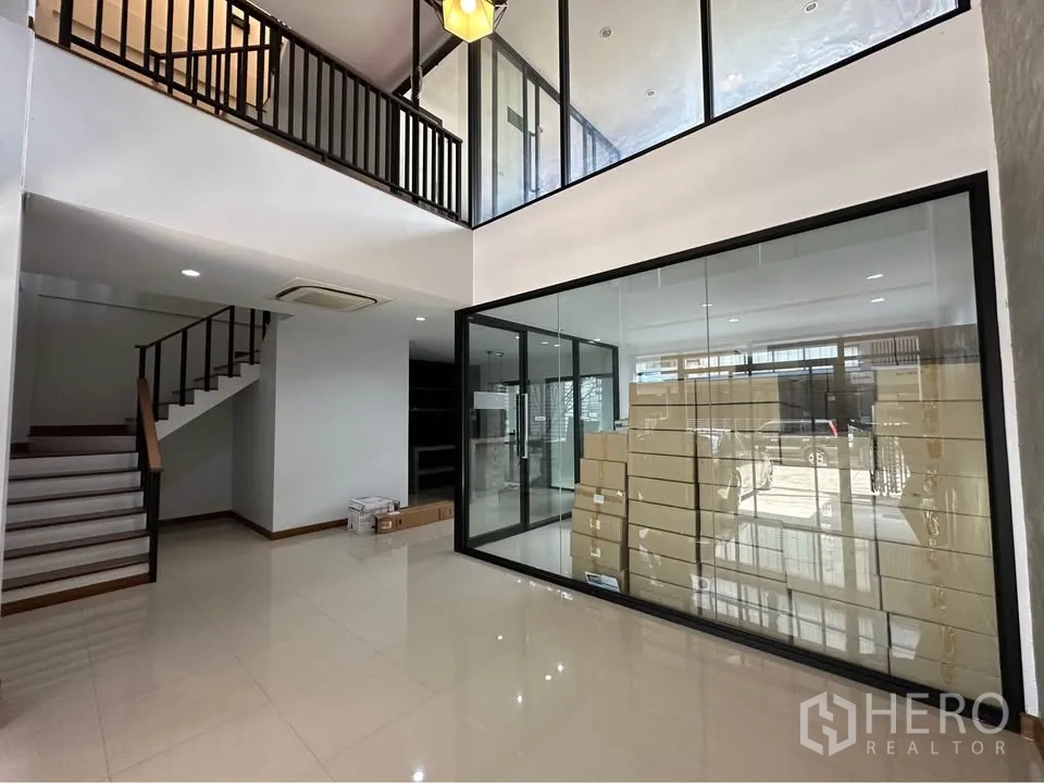 联排别墅 出租在Pak Kret, Nonthaburi - 挑高大厅，中置玻璃会议室与楼梯。