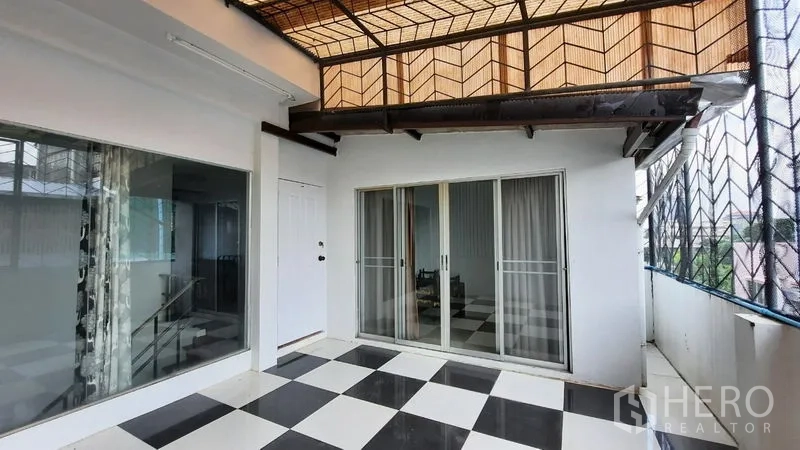 Townhouse for rent or sale in Suan Luang, Bangkok - Covered terrace with black-and-white checker tiles and sliding doors.