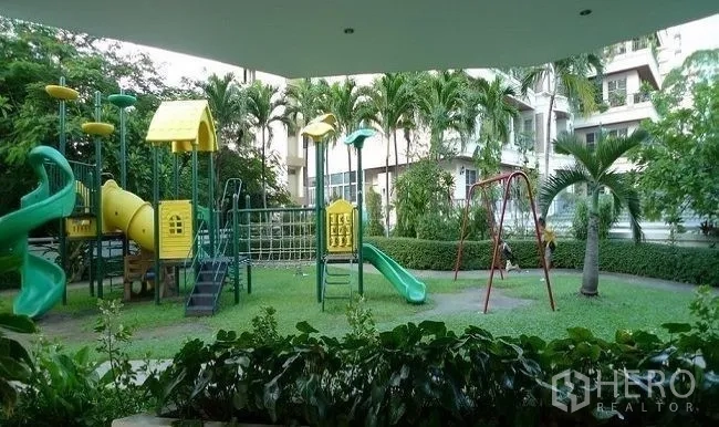 Condominium for rent in Watthana, Bangkok - Landscaped children’s playground with slides, swings and climbing frames surrounded by palms and greenery.