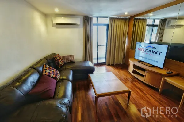 公寓 出租在Watthana, Bangkok - 客厅，L形真皮沙发、茶几与通往阳台的玻璃门