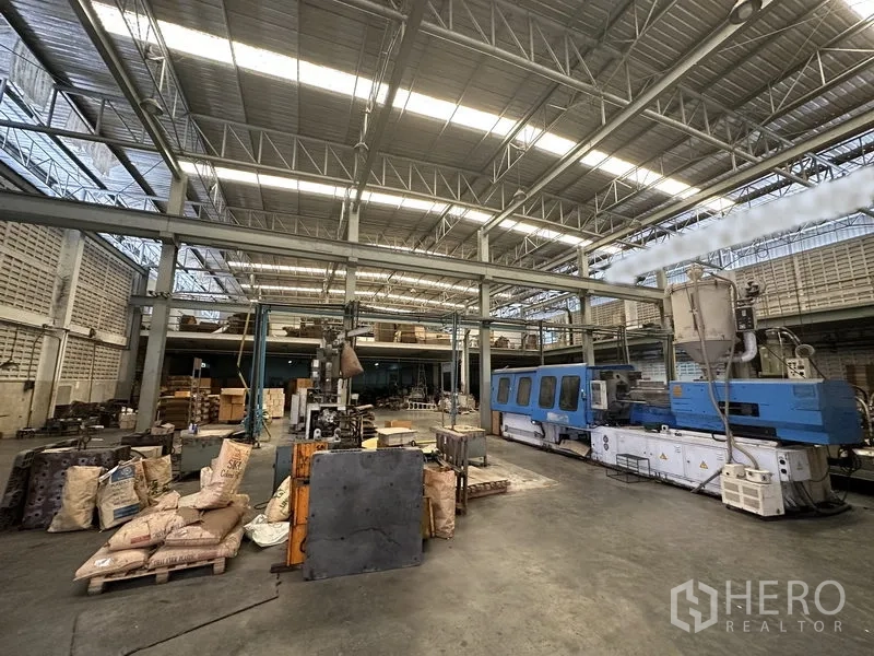 Factory for rent or sale in Lam Luk Ka, Pathum Thani - High-bay manufacturing hall with steel truss roof and heavy machinery.