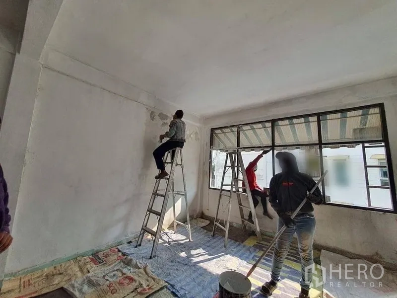 Shophouse for rent in Bangkok - Spacious room with long horizontal windows and ladders, surfaces prepared for renovation.