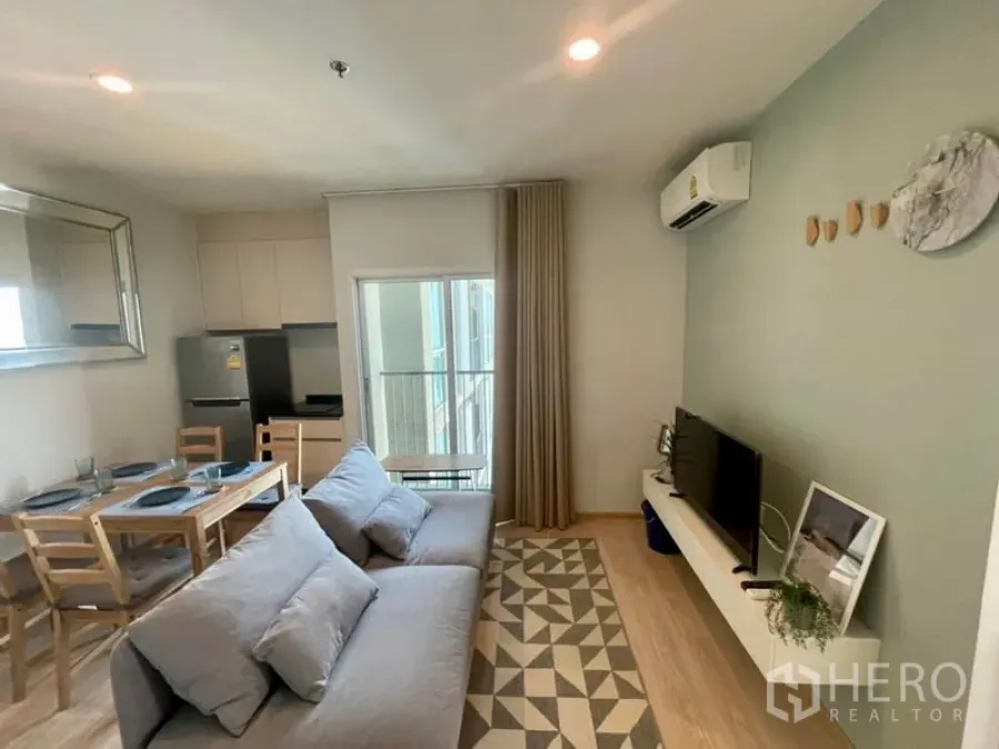 คอนโด ให้เช่าในHuai Khwang, Bangkok - ห้องนั่งเล่นสว่าง โซฟาสีเทา ชั้นวางทีวี ระเบียง และครัวทานข้าว