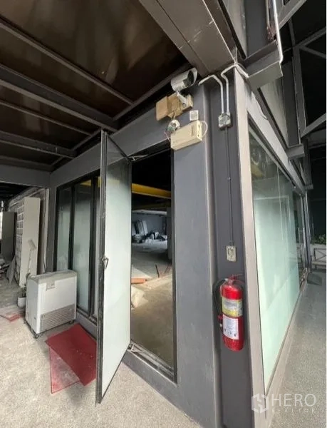 Retail Space for rent in Watthana, Bangkok - Corner entrance with open glass door, fire extinguisher and exposed building services.