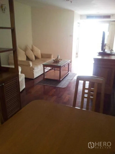 Condominium for rent - Living area with cream sofa, coffee table and TV on polished wooden flooring.