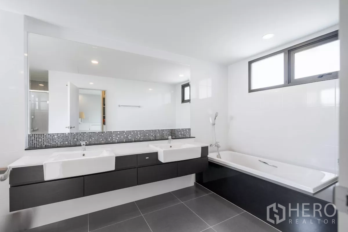 Detached House for sale in Saphan Sung, Bangkok - Main bathroom with double vanity and bathtub under windows.