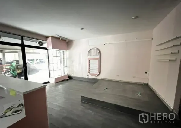 Shophouse for rent in Watthana, Bangkok - Main retail area with large display windows, gray tile floors, a raised platform, and service counter.