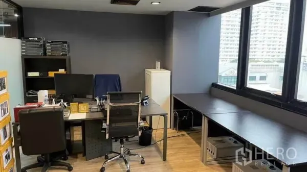 Office Space for rent in Khlong Toei, Bangkok - Corner office area with large windows, dark feature wall, multiple desks and shelving units.