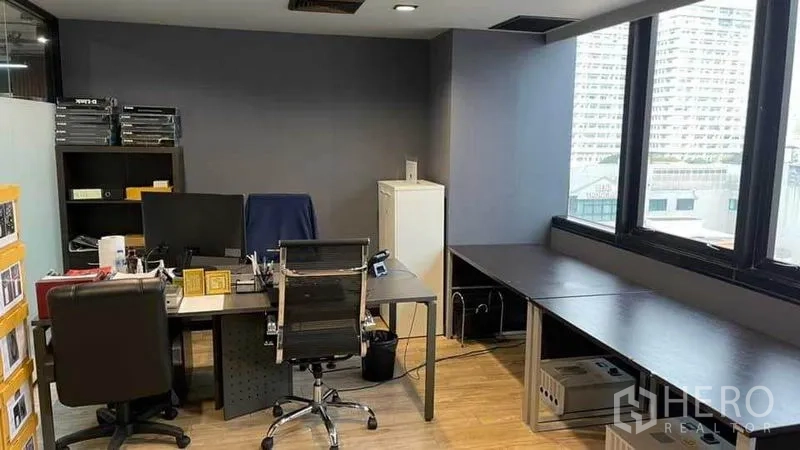 Office Space for rent in Khlong Toei, Bangkok - Corner office area with large windows, dark feature wall, multiple desks and shelving units.