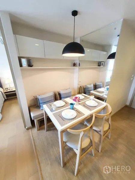 Condominium for rent in Watthana, Bangkok - Cozy dining nook with built-in bench seating, wall shelves and a black pendant lamp.