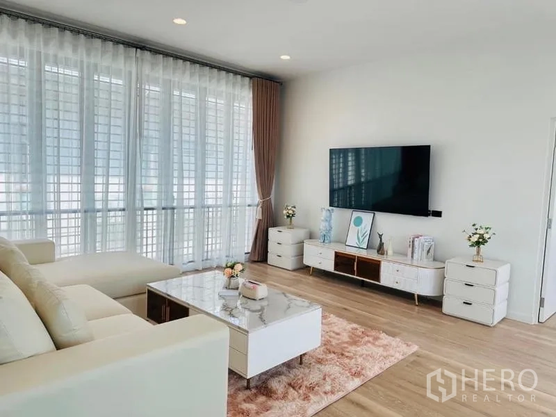 Detached House for rent or sale in Bang Kapi, Bangkok - Living room from another angle showing TV wall, pink rug and expansive windows for natural light.