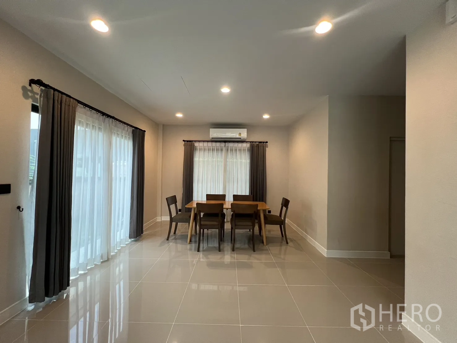 Detached House for rent in Bang Kapi, Bangkok - Dining area with a six-seat table, windows and curtains.