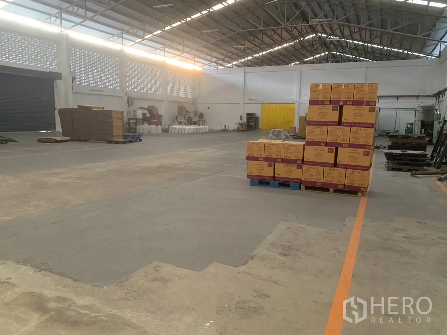 仓库 for rent in Bang Phli, Samut Prakan - 宽敞仓库内景，钢桁架屋顶，托盘纸箱与地面划线。