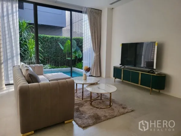Detached House for rent in Wang Thonglang, Bangkok - Bright living room with sofa and TV console opening to a private swimming pool through sliding glass doors.