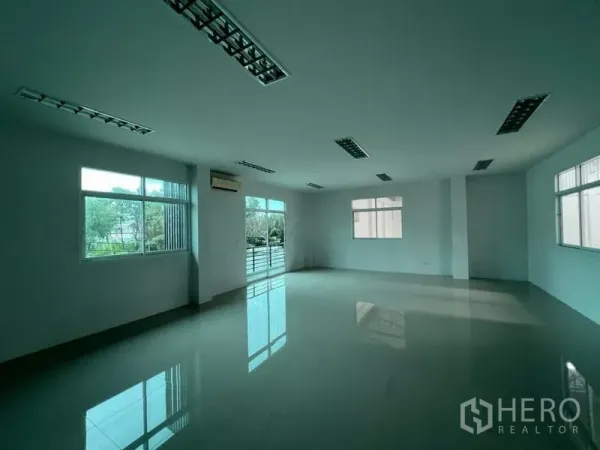 Factory for rent in Phra Samut Chedi, Samut Prakan - Bright mezzanine office with polished floors, fluorescent lighting and multiple windows facing greenery.